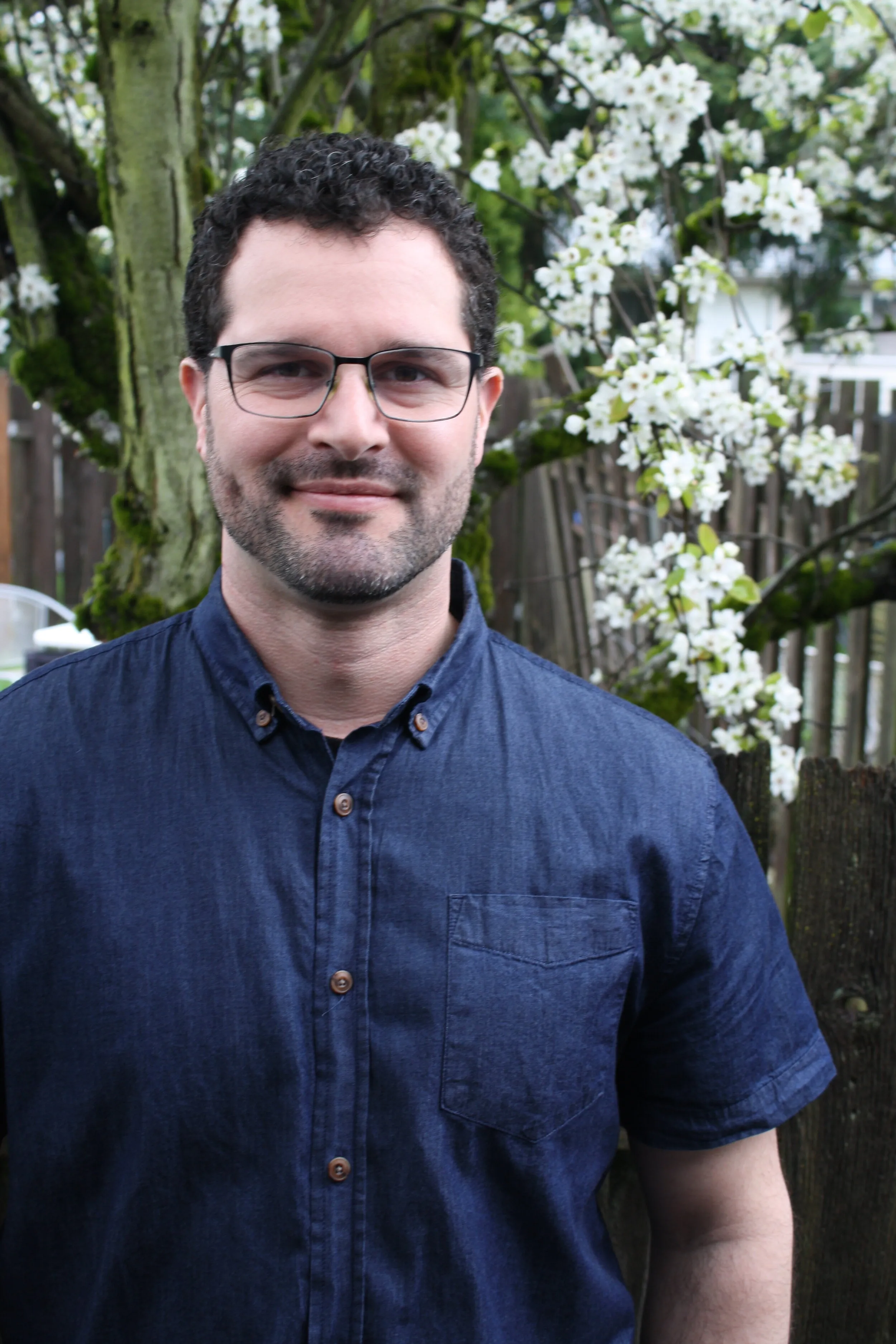 Brandon Johnson, standing outdoors in front of a flowering tree.