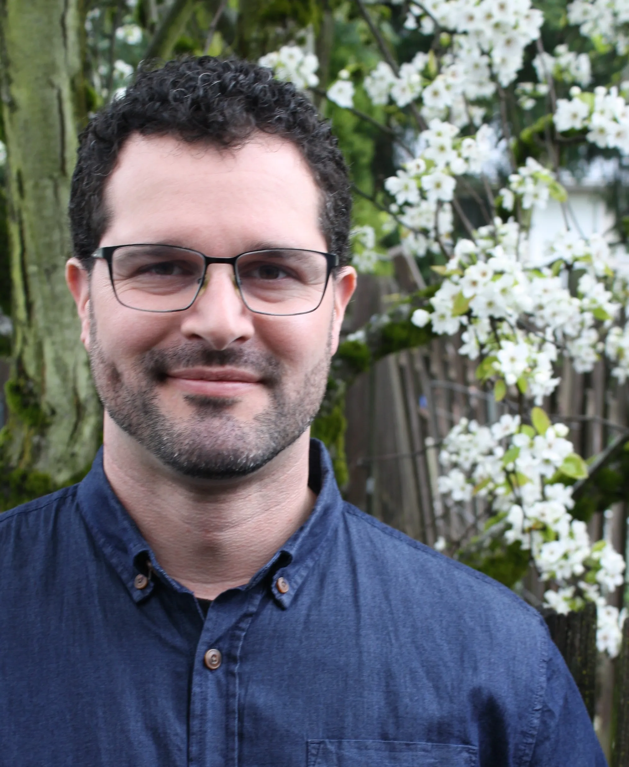 Brandon Johnson, standing outdoors in front of a flowering tree.